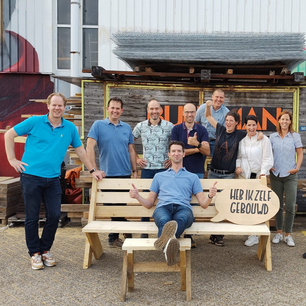 Bouw het zelf Teambuilding bij Buurman Rotterdam. Een groep met hun eigen gemaakte buitenbank, met voeten kruk.