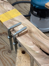Tijdens de cursus hout kennis en reparatie wordt een nieuw stuk essen hout in een uitsparing gelijmd om het hout te repareren.