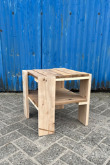 Een bijzettafel naar ontwerp van Rietveld uit de Krat serie. De bijzettafel heeft een reparatie aan een van de poten. Er is dwars een reep hout ingelijmd om te voorkomen dat het hout verder uitscheurt.
