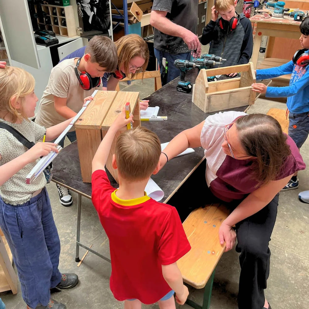 Kinderen zijn bezig met meten en tekenen hout tijdens een oudere en kind workshop.