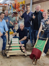 Teambuilding Design Challenge, een circulaire klus wedstrijd bij Buurman Rotterdam. Team met hun creaties, een vliegenvanger en tijdschriften rek lamp, uitvouwbaar strand zitje met uitklapbare plateaus voor je drankjes, en een krui en kinder wagen sjoelbak.
