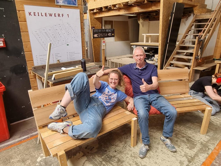 Deelnemers van de workshop bouw een bankje trots op hun eigen gemaakte tuin bankjes.