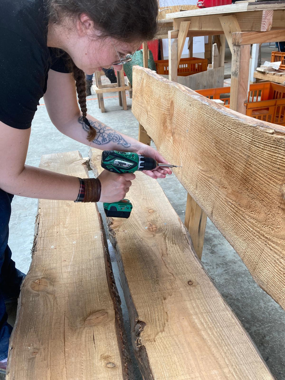Deelnemer aan het werk tijdens de workshop bouw een bankje. Vastschroeven van de rugleuning.