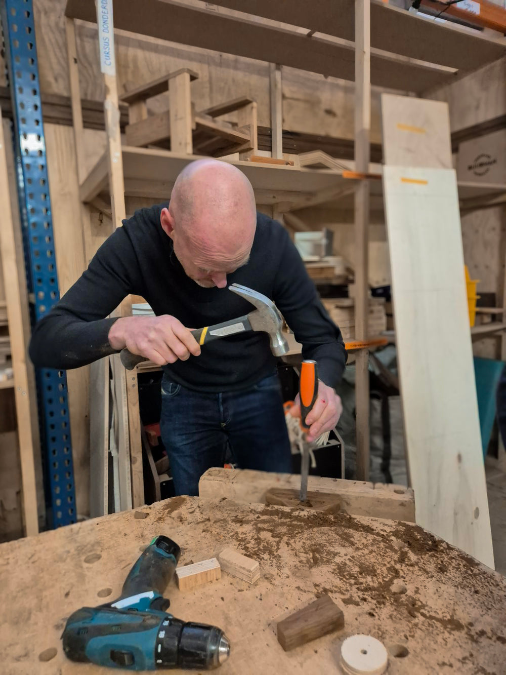 Een man is tijdens de workshop houten speelgoed maken, een raam in een houten autootje aan het beitelen.