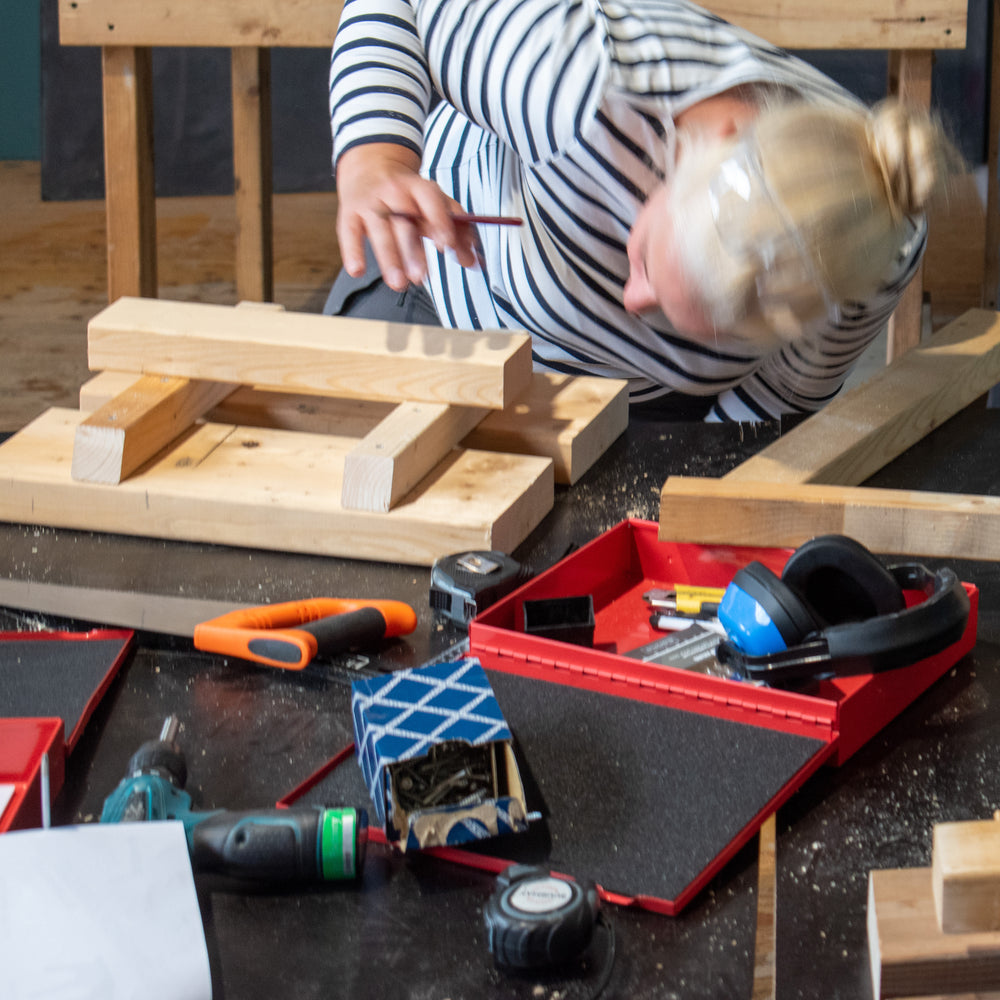 Een vrouw is tijdens de workshop Japans krukje het hout voor haar krukje aan het passen.