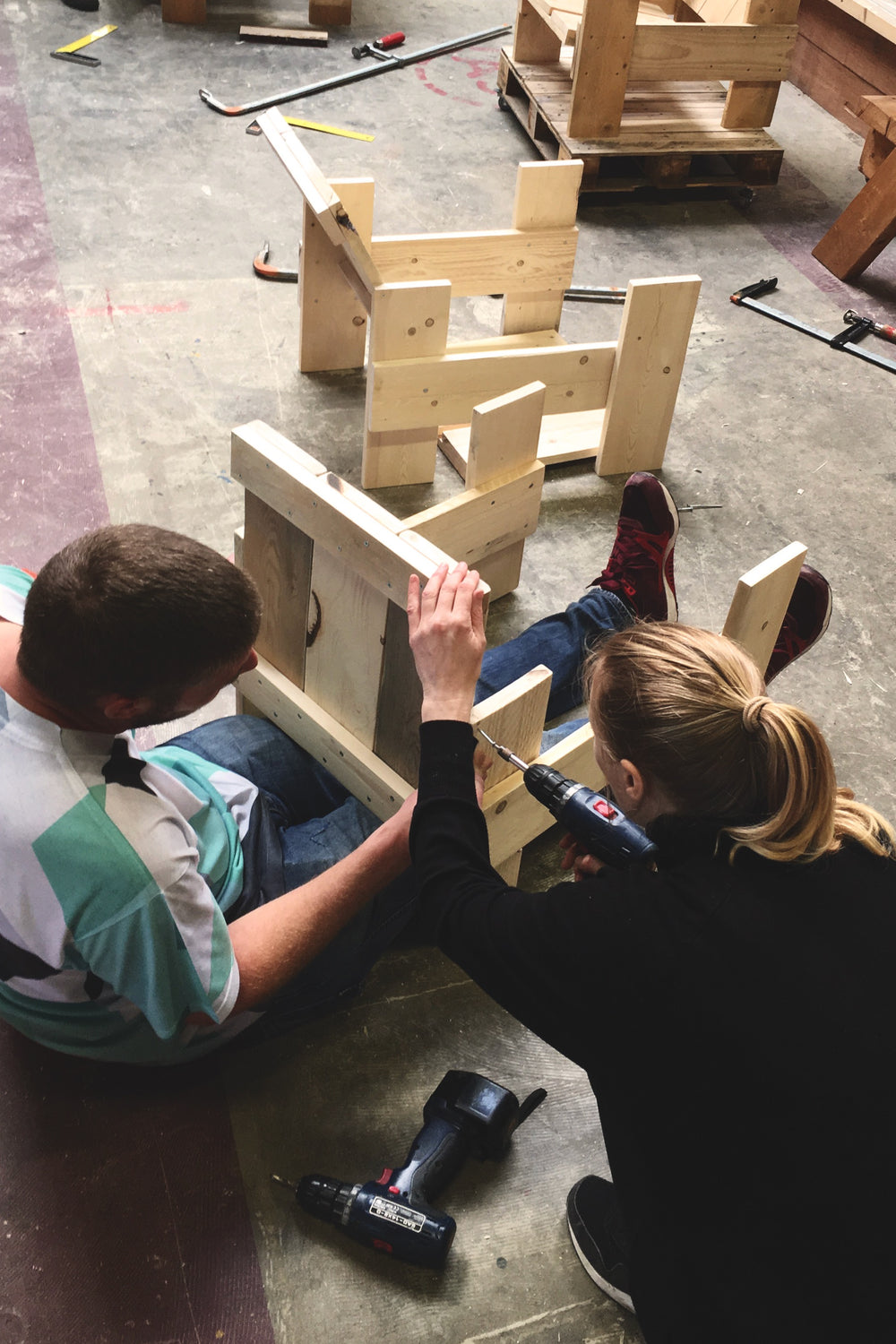 Twee deelnemers van de workshop Rietveld stoel samen aan het werk. Delen van de stoel worden aan elkaar geschroefd.