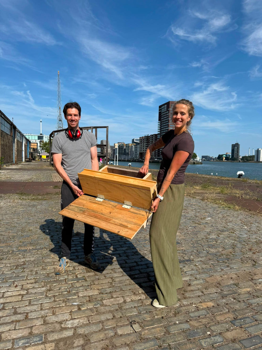 Twee deelnemers van de workshop Bouw een Balkonbar, tonen hun eigen gemaakte balkonbar met inklapbaar tafeltje en plantenbak.